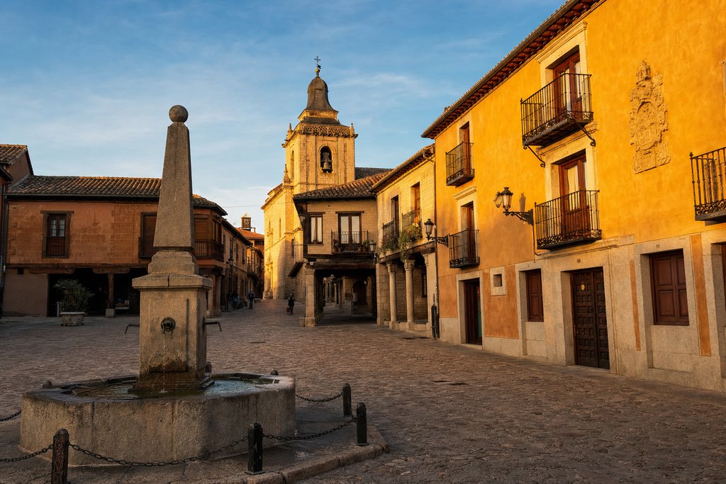 A historic Valdemoro plaza with a stone fountain at golden hour